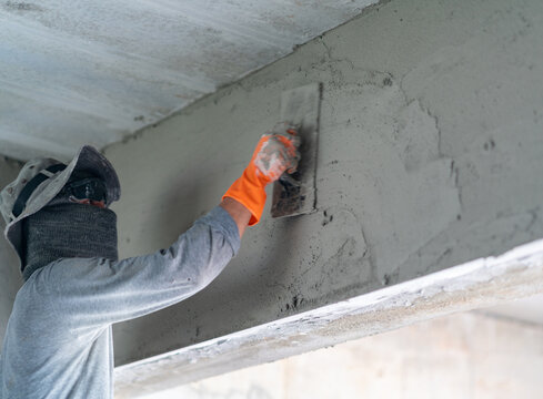 Construction worker plastering a concrete wall surface during house renovation.