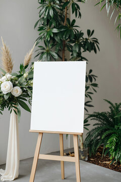 Vertical 18x24 wedding sign mockup on a wooden easel with blank white poster and floral arrangement.