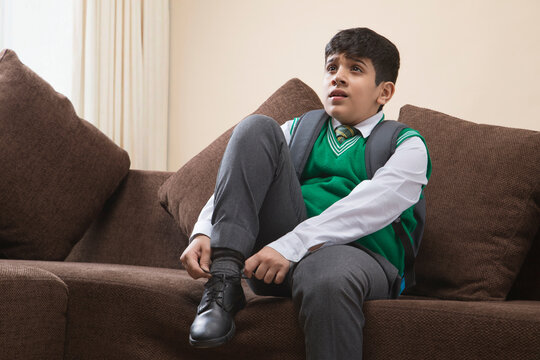 School Boy tying shoes at home