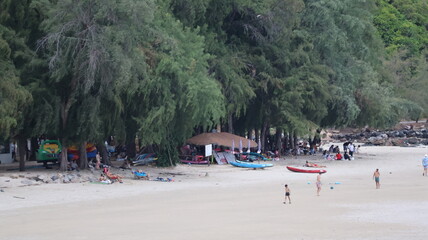 Fototapeta premium The image depicts a beach scene with a wide stretch of sand and several people scattered across the area, some walking and others lounging