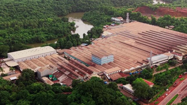 Large tyre factory spread across a valley below forested green hills