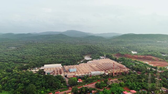 Tyre manufacturing plant with long production sheds set against forested hills