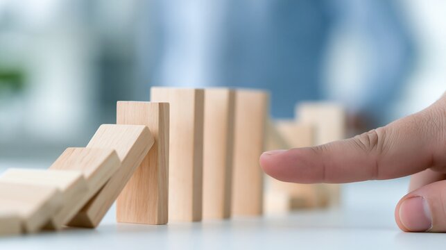 Hand nudging wooden blocks in a line, initiating a chain reaction and predicting consequences