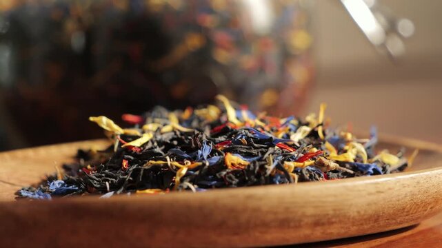 Close-up of colorful loose leaf herbal tea blend in a wooden bowl. Aromatic dried flowers, herbs and tea leaves create a natural wellness and healthy beverage concept with warm, cozy atmosphere. High