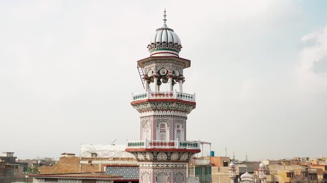 Ornate Mosque Minaret with Loudspeakers Above Urban Neighborhood