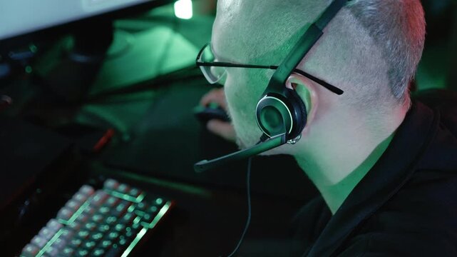 Professional programmer with headset typing code on a computer in a dark office