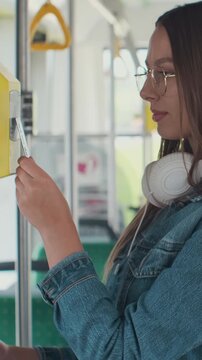 Vertical video. Woman paying contactless with bank card for the public transport in the tram.