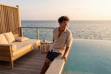 Fototapeta premium Man relaxing on luxury resort overwater bungalow terrace at sunset