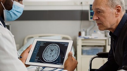 Obraz premium Professional physician presenting neurological imaging on tablet while consulting patient in modern healthcare clinic.