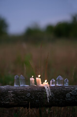 Obraz premium clear quartz crystals and burning candles outdoor, abstract dark natural evening background. Witchcraft, Esoteric spiritual ritual, practical magic for life balance, cleansing aura. soft focus
