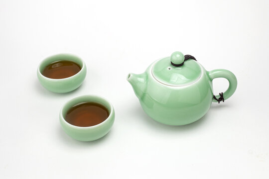 Traditional light green celadon ceramic teapot with two teacups filled with hot tea isolated on white background