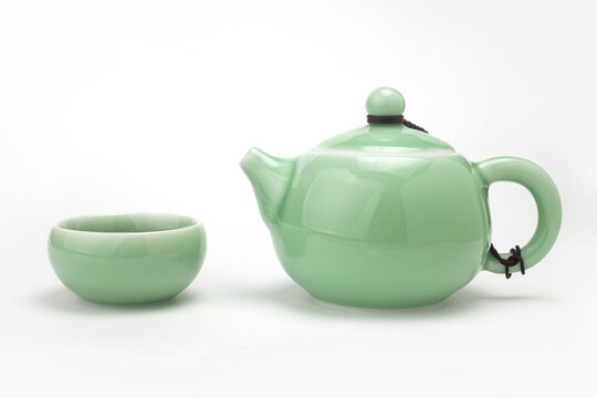 Traditional light green celadon ceramic teapot with one teacup filled with hot tea isolated on white background