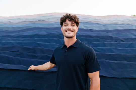 Smiling man in navy polo against layered blue fabric waves for portrait and banner use
