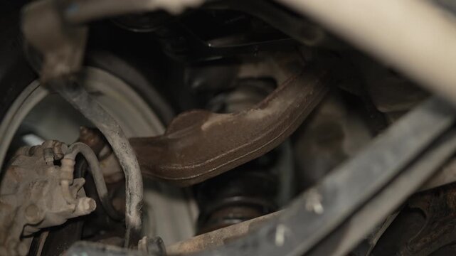 A view of a car's rear suspension coil spring and upper control arm.