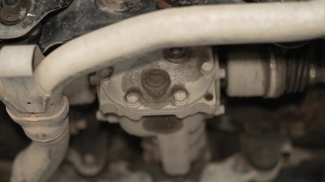 A close-up view of a car's rear differential housing with oily sweat around the plugs.