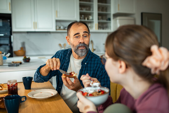Father and daughter eating breakfast in home kitchen