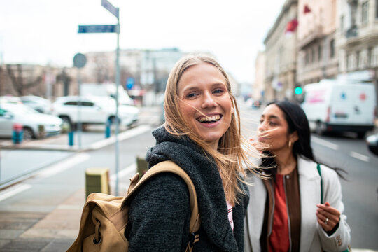 Two friends smiling while walking on city street
