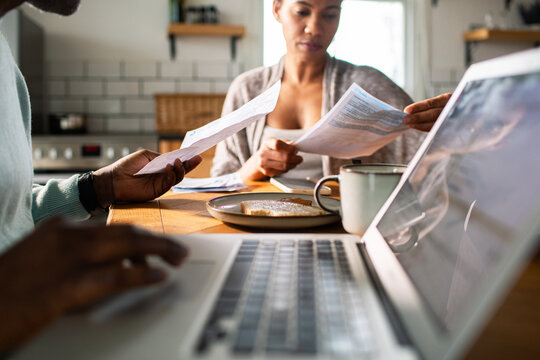 Couple paying bills online at kitchen table