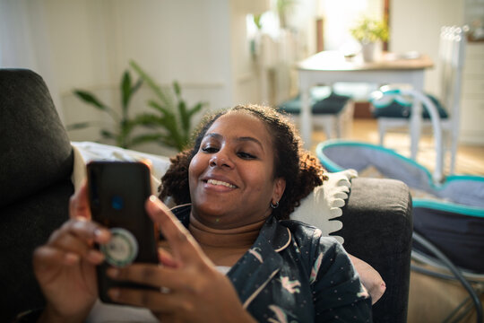 Smiling woman using smartphone on couch at home
