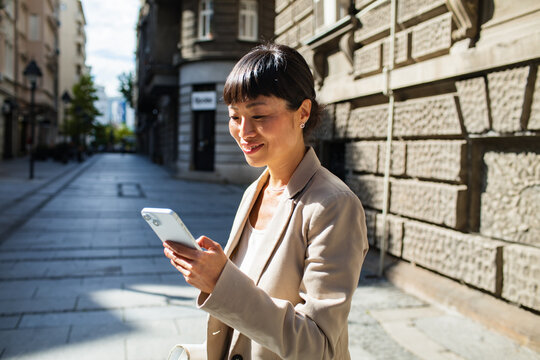 Smiling woman using smartphone on city street