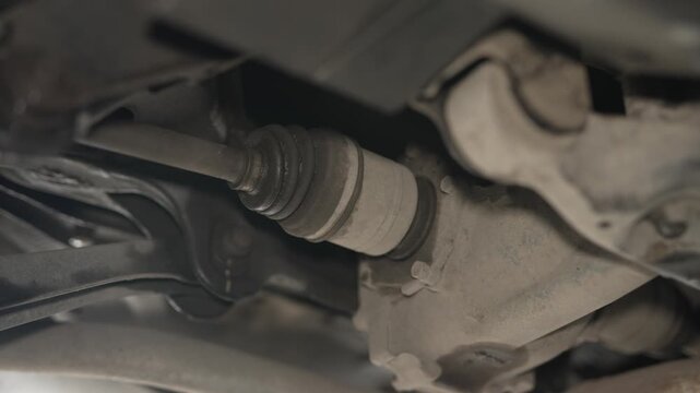 A car drive shaft and rubber CV joint boot connected to the differential housing.