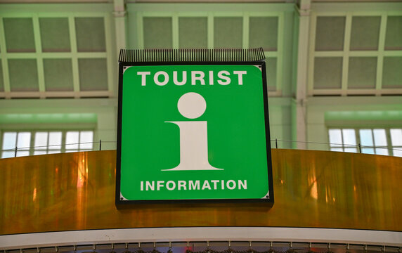 Green tourist information sign with illuminated white i symbol. Tourist information sign displaying white information icon. Illuminated tourist information counter sign in green color.
