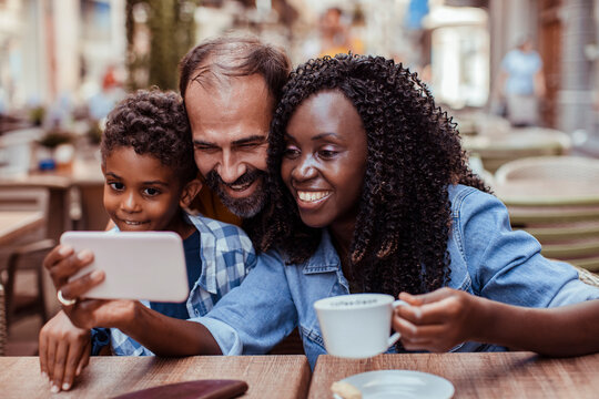 Happy parents and son taking selfie at outdoor cafe
