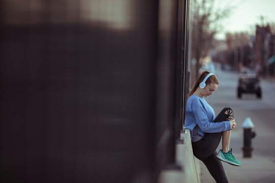 Young woman stretching after run on city sidewalk