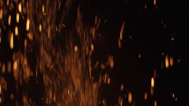 黒背景に垂直に降り注ぐ赤く光る残り火と灰