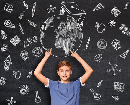 Online education in school. Inspired teenage boy getting good education, holding globe with graduation hat above his head, board with educational icons on, collage