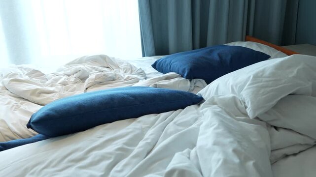 Portable rollaway extra bed with untidy linens prepared for housekeeping after guest checkout.
