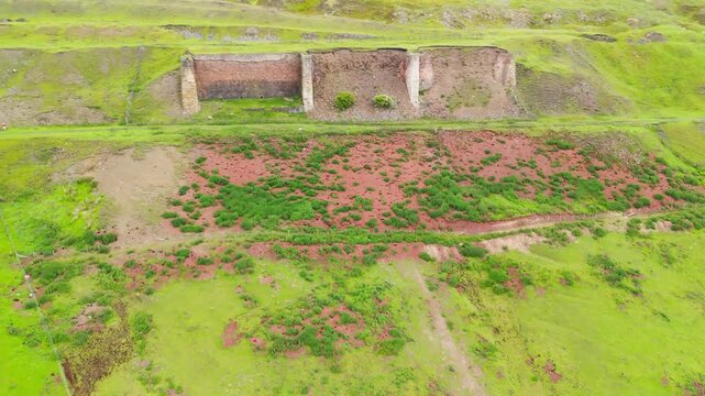 Aerial drone view of the abandoned historic stone ironstone kilns in Rosedale Abbey, set against overcast rolling Yorkshire hills.