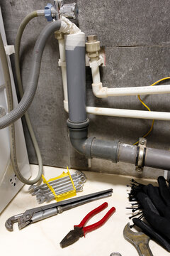 Vertical orientation plumbing tools wrench and pipes under bathroom sink installation or repair process water filtration system apartment maintenance sewage pipeline renovation home improvement handym