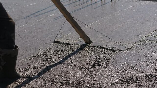 Drawing fresh concrete with screed board during slab pouring close up