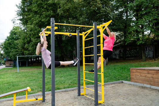 Women exercising on outdoor gym equipment in a park during the day