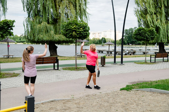 Women walking and waving in a park near a lake during the day