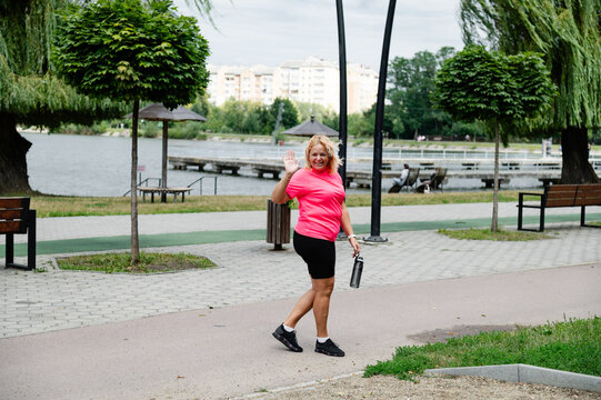 Woman walking in a park by the water with a bottle in her hand