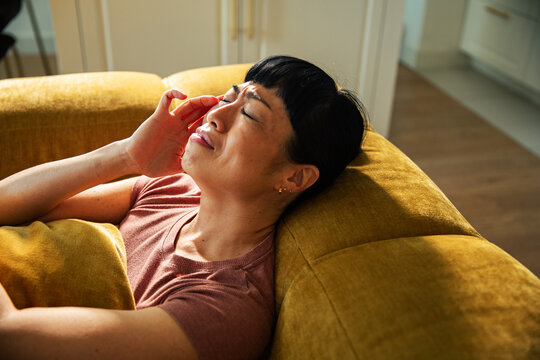 Tired woman in pain from a migraine at home