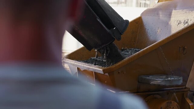Pouring fresh concrete into concrete pump hopper during construction