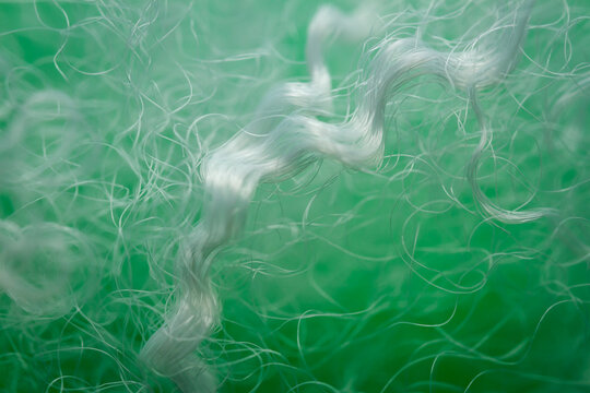 Extreme macro of polyester stable fiber on green background. Selective focus, shallow depth of field. Abstract dreamy background