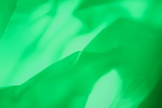 Extreme close up of green plastic texture background. The plastic surface is wrinkly and tattered making abstract pattern. Selective focus, shallow depth of field.