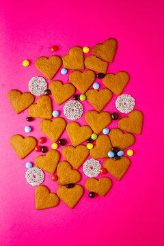 Top view of candies and heart shaped cookies on a vibrant pink background. Dessert photography, sweet treats.