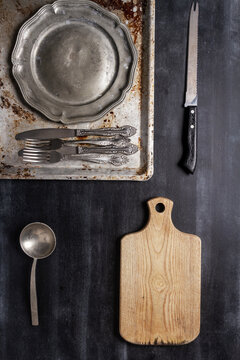 Old various kitchen utensils on black chalkboard background. Food themed flat lay.