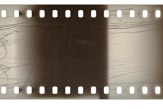 Dusty and grungy 35mm film texture or surface. Perforated scratched camera film isolated on white background.
