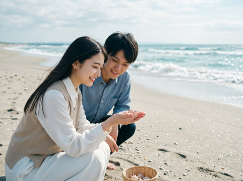 手のひらの貝殻を優しく見つめるニットベスト姿の女性