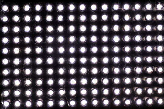 close-up grid pattern of multiple glowing white LED lights set against a black surface.