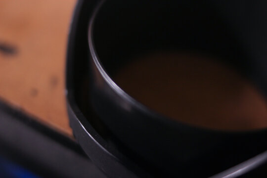 lose-up abstract view of a black camera lens hood resting near a warm wooden surface with shallow depth of field.