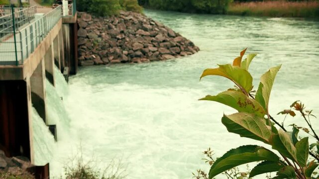 Small hydroelectric station on the Drac River in France with flowing water, concrete floodgates and surrounding vegetation. Renewable energy, hydropower and green electricity concept