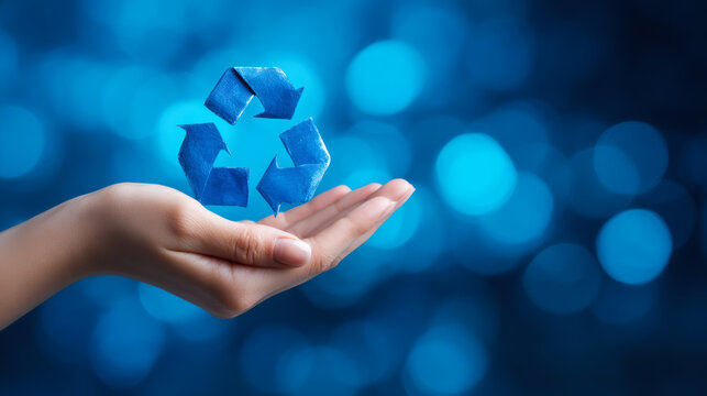 Recycling symbol above open hand shows commitment to environmental protection and sustainability during daytime with blue background