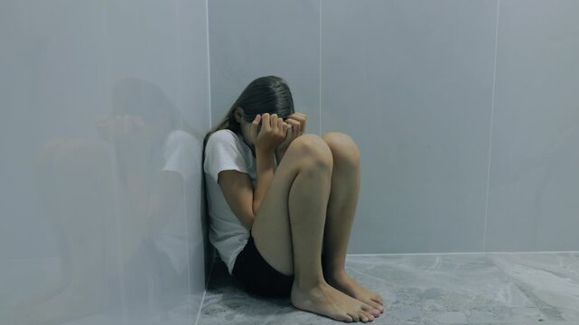 Anxious zoomer minor hiding face in corner of an empty room.